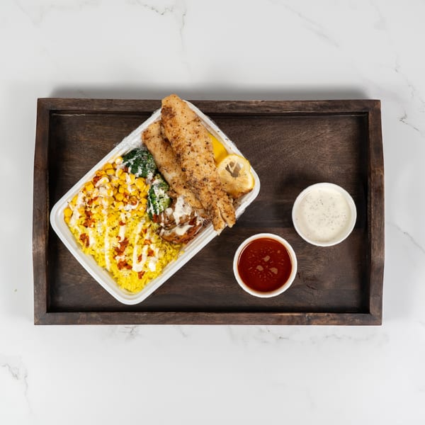 Grilled fish fillets with yellow rice, corn, broccoli, and two dipping sauces on a wooden tray.