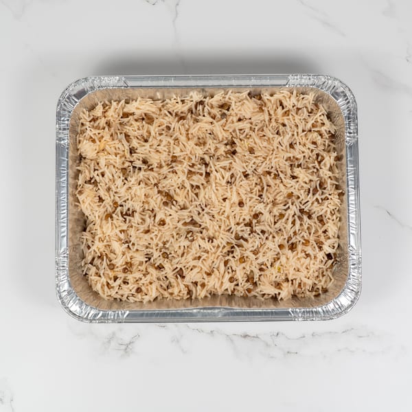 A large aluminum tray filled with light brown rice and lentils, viewed from directly above.